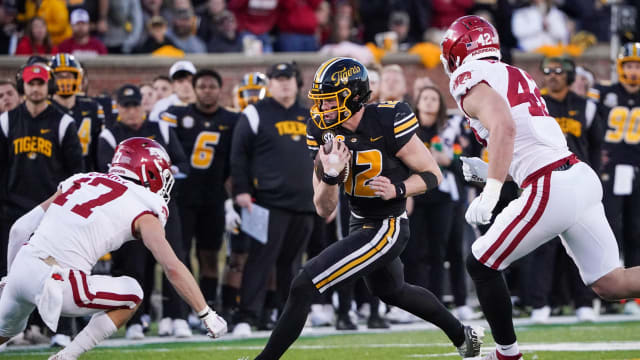 Nov 25, 2022; Columbia, Missouri, USA; Missouri Tigers quarterback Brady Cook (12) runs the ball as Arkansas Razorbacks defensive back Hudson Clark (17) and linebacker Drew Sanders (42) defend during the second half at Faurot Field at Memorial Stadium. Mandatory Credit: Denny Medley-USA TODAY Sports